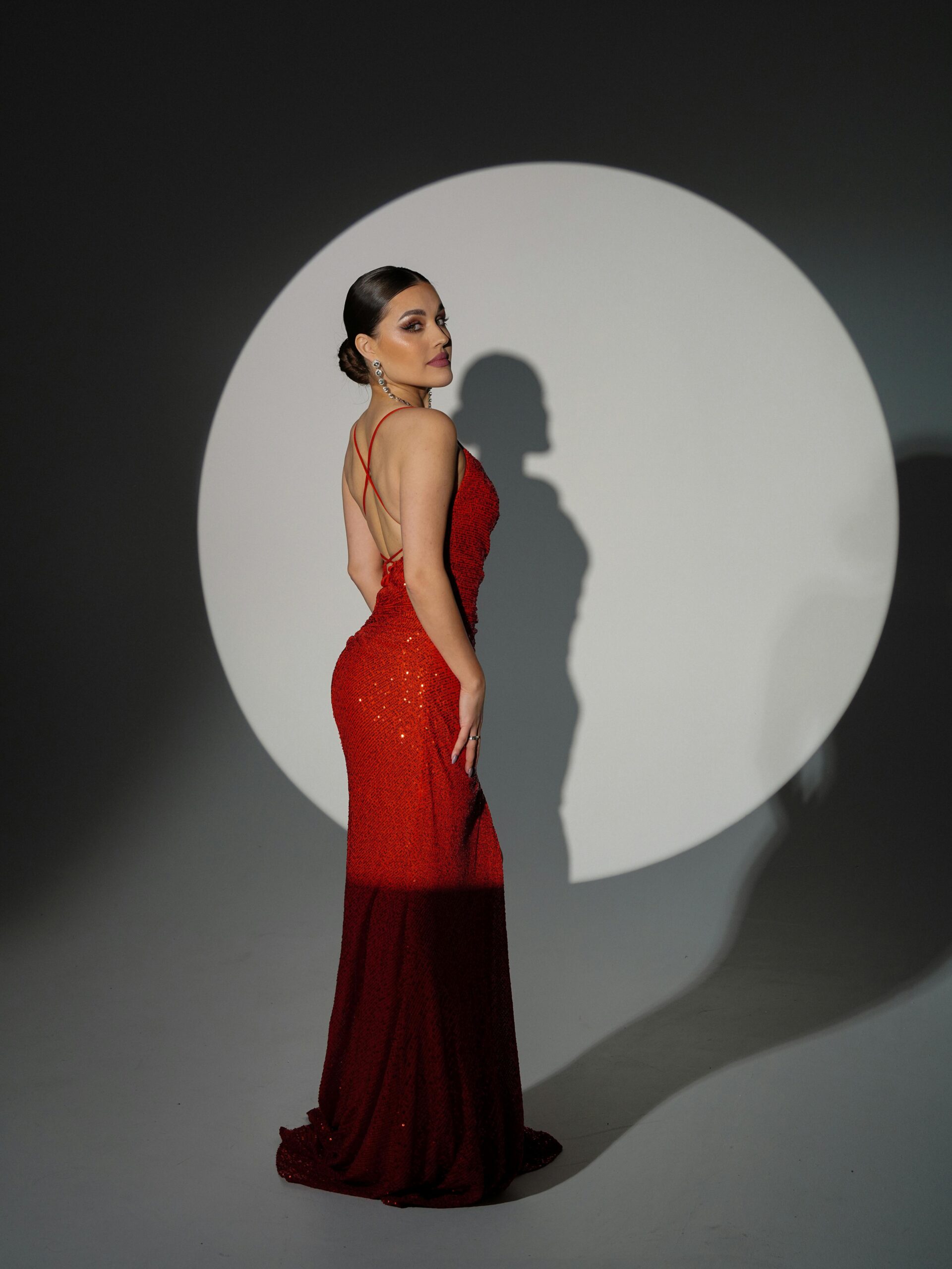 Striking fashion model in a red gown against a contrasting white circle background.