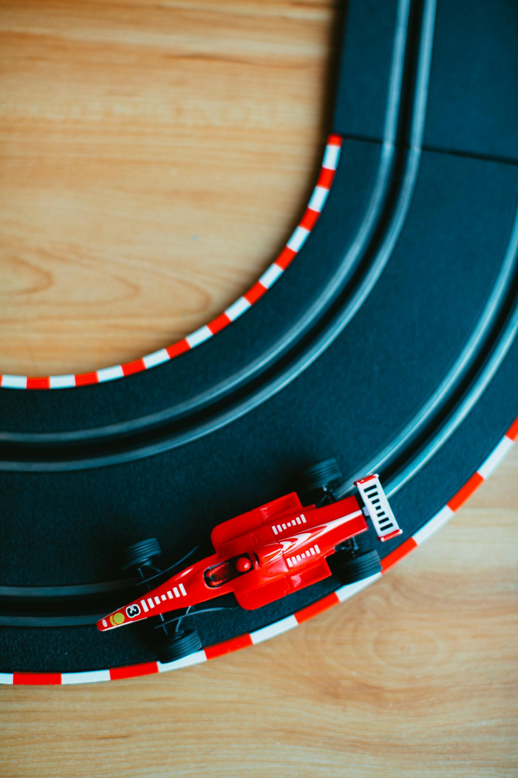 High-angle shot of a red Formula 1 toy car on a racetrack, showcasing vibrant color and detail.